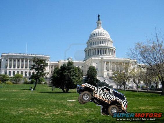 Off-road vehicle with zebra stripes doing a jump in front of the Capitol building