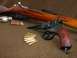 2003 Ford Crown Victoria - A close-up view of a revolver and rifle, accompanied by several rounds of ammunition, arranged on a textured brown background.