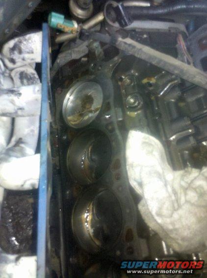 Engine block with pistons and blown gasket. Supermotors.net logo visible