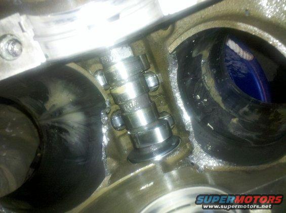 Close-up of engine camshaft with lifters and valve springs visible inside a cylinder head