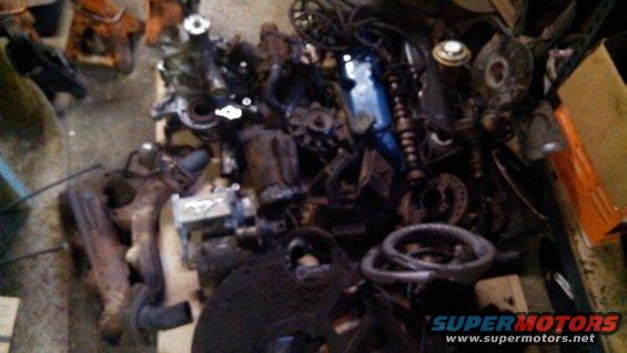 Pile of assorted engine parts including exhaust manifolds and a blue valve cover