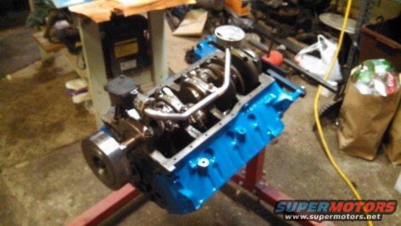 Blue engine block on a red stand, showing crankshaft and connecting rods