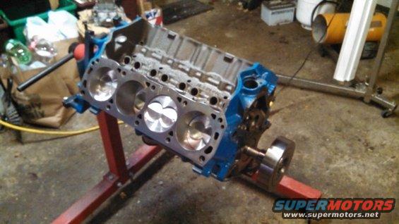 Blue engine block with pistons on a red stand