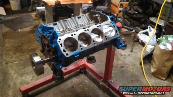 Blue engine block with pistons visible, mounted on a red engine stand