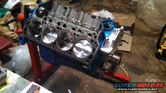 Engine block with pistons visible, mounted on a red stand
