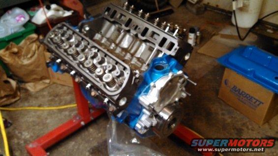 Blue engine on red stand, with a blue valve cover on a box