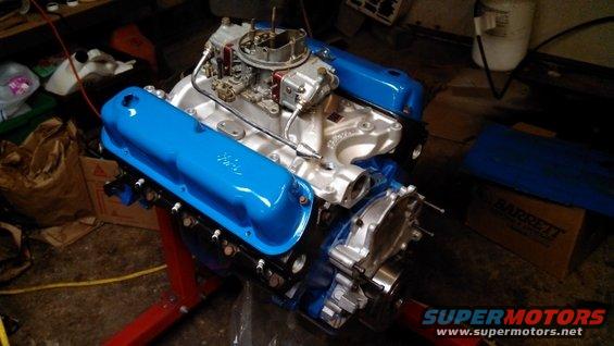 Ford V8 engine with blue valve covers on a red stand
