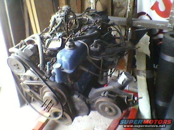 Engine assembly on an orange stand, with belts and pulleys visible