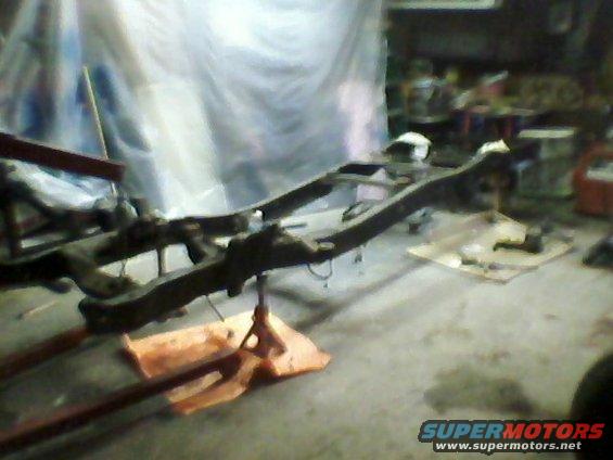 Truck frame on jack stands, covered in dust and grime, in a workshop
