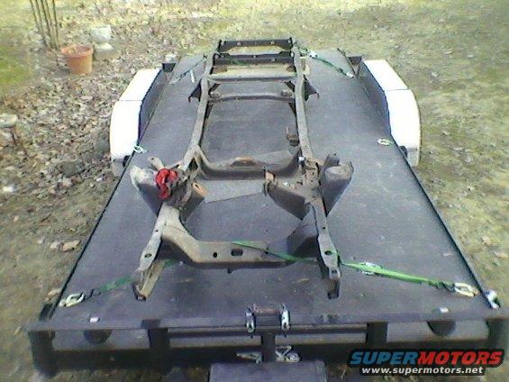 Truck frame secured with green straps on a flatbed trailer