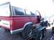 1987 Ford Ranger - A red 1987 Ford Ranger pickup truck with a white camper shell is loaded onto a trailer, with another white truck visible behind it.