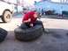 1987 Ford Ranger - Person working on a large tire with a tool, with another tire nearby.