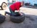 1987 Ford Ranger - A person works on a large tire in an outdoor setting with another vehicle visible in the background.