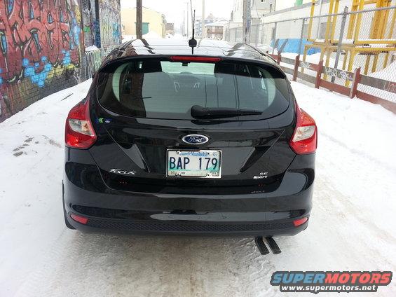 Rear view of a black Ford Focus SE Sport hatchback parked on a snowy street next to a graffiti-covered wall