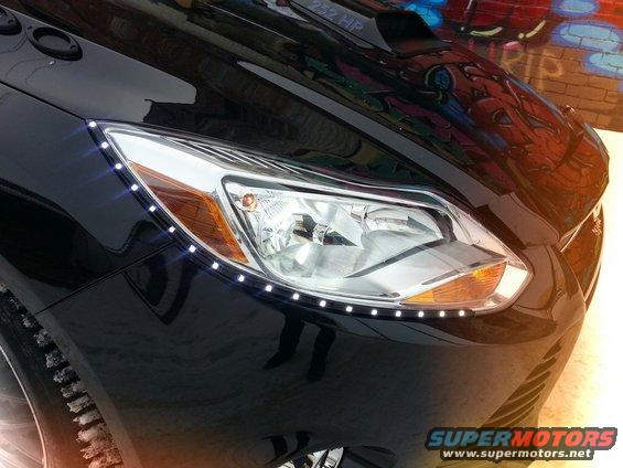 Black car with LED strip lights around the headlight. Hood has text that says '232 HP'