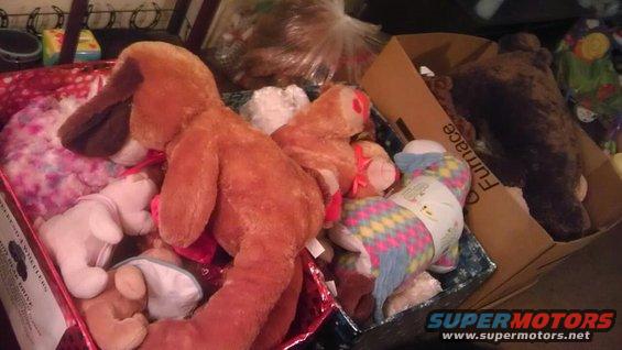Box of stuffed animals including a large brown dog, a rainbow unicorn, and a teddy bear