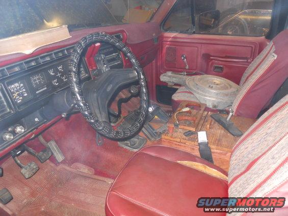 Interior of a 1980 Ford Bronco, red dashboard and seats, steering wheel