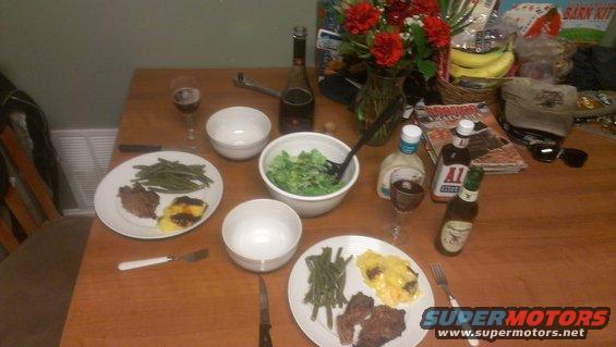 Table set for dinner with plates of steak, green beans, and casserole