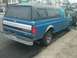 1993 Ford Bronco - This blue Ford pickup truck features a black camper shell and chrome tailgate trim, seen from the rear.