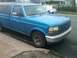 1993 Ford Bronco - This blue Ford F-150 pickup truck features a black camper shell and is parked curbside.