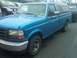 1993 Ford Bronco - This blue 1993 Ford F-150 pickup truck is seen from the front-three-quarter angle, equipped with a camper shell.