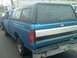 1993 Ford Bronco - Blue Ford pickup truck with a camper shell is parked next to another vehicle.