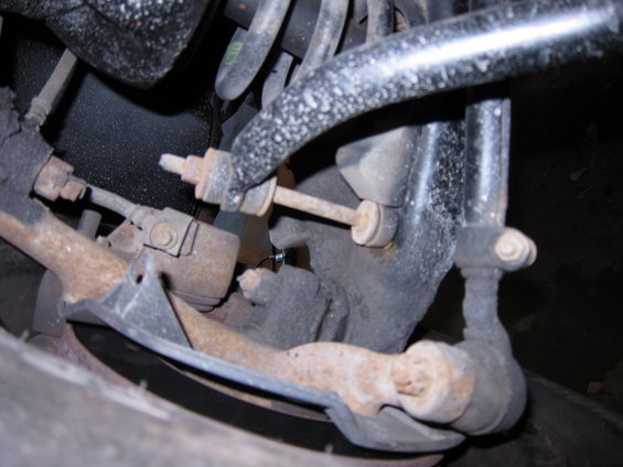 Close-up of rusty car suspension components including tie rod and sway bar link