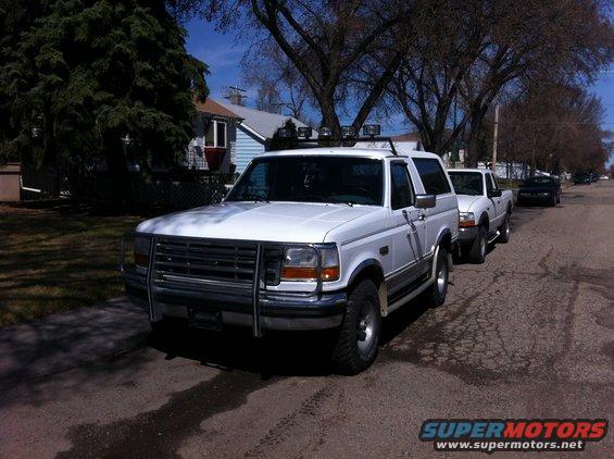 White Ford Bronco with a brush guard and roof lights parked on a street