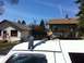 1994 Ford Bronco - A white SUV's roof is visible with a cargo rack overhead, set against a backdrop of houses and a clear blue sky.