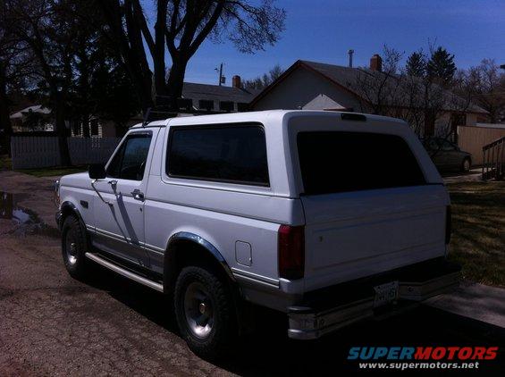 White SUV, rear 3/4 view, with roof rack
