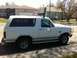 1994 Ford Bronco - A white Ford Bronco is parked on a residential street under a clear sky.