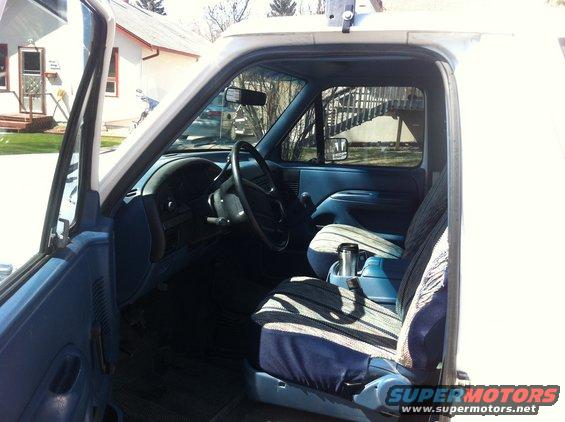 1994 Ford Bronco interior showing blue dashboard, steering wheel, and striped seat covers
