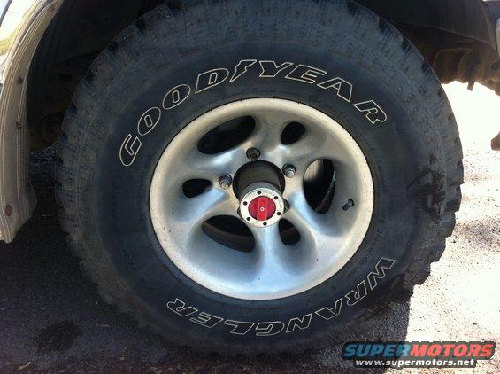 Close-up of a Goodyear Wrangler tire on a silver 5-spoke wheel with a red and silver hub