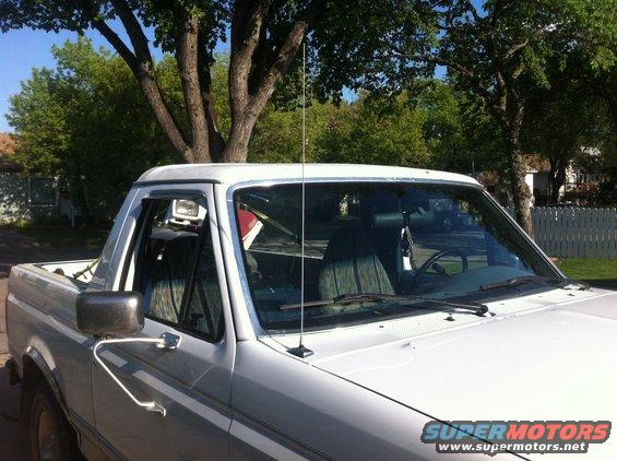 White Ford Bronco from the front passenger side, showing the side mirror, door, and part of the windshield and roof