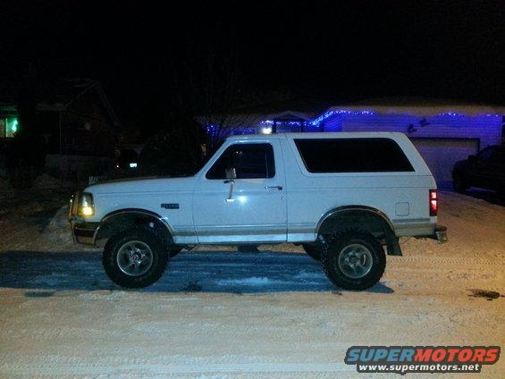 White 1994 Ford Bronco side view parked in snow at night