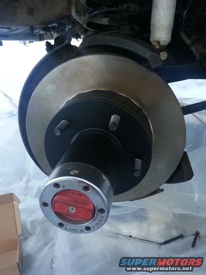 Close-up of a vehicle's front brake rotor and hub assembly with a red locking mechanism labeled 'LOCK' and 'FREE'