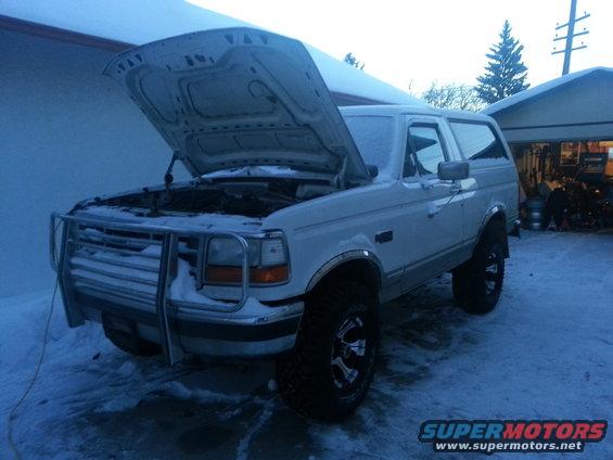 White Ford Bronco with hood open, parked in snow. Bull bar on front. Aftermarket wheels