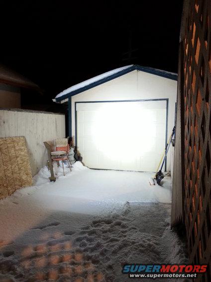 Snow-covered driveway in front of a garage door at night