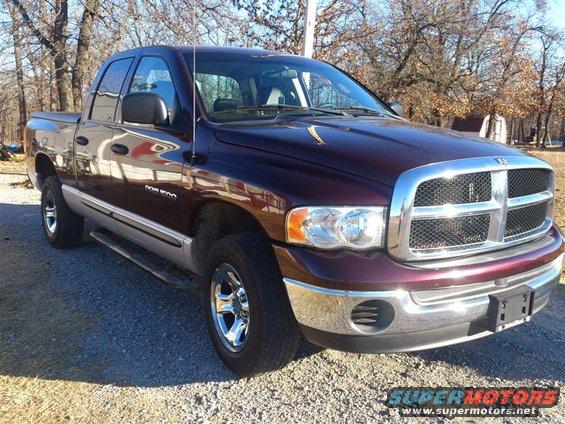 Maroon and silver Dodge Ram 1500 pickup truck, front 3/4 view, parked on gravel