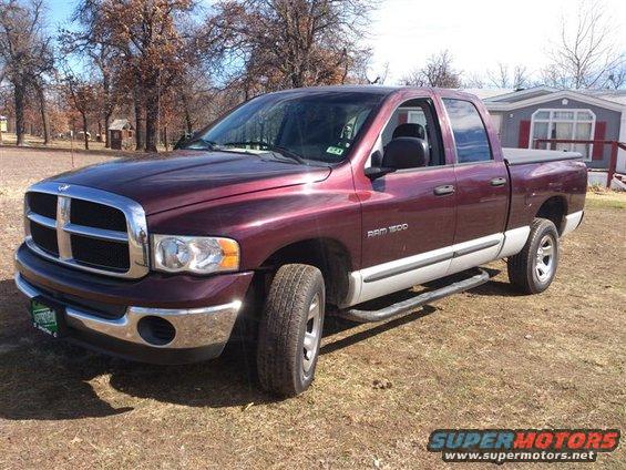 Maroon 2004 Dodge Ram 1500 pickup truck with a silver lower body and black tonneau cover, parked on dry grass