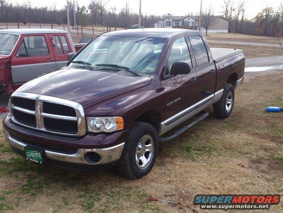 Maroon Dodge Ram pickup truck parked outside, another red truck partially visible
