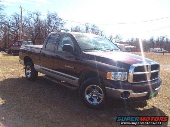 Maroon Dodge Ram 1500 pickup truck, 3/4 front view, with a tonneau cover and chrome wheels