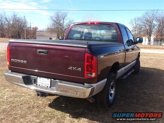 Maroon pickup truck with a tonneau cover, chrome bumper, and 4x4 badging, viewed from the rear