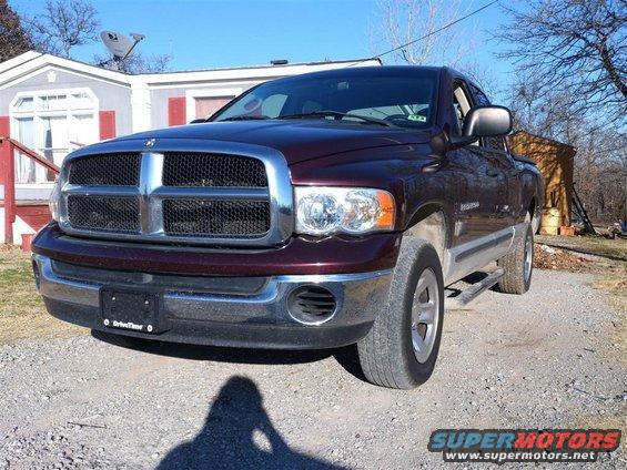 Front view of a maroon Dodge Ram pickup truck parked on a gravel driveway