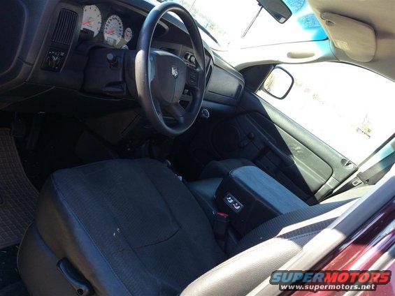 Dark fabric truck interior with a steering wheel, dashboard, and seats visible. The armrest has buttons