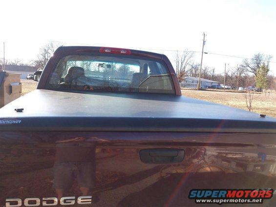 Red Dodge pickup truck rear view with tonneau cover and "DODGE" badging