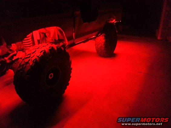 Off-road vehicle tires and undercarriage illuminated by red lights