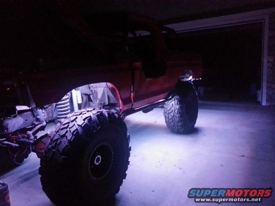 Red SUV with large tires and purple underglow lights, side view