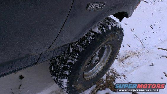 Dark 1995 Ford Bronco XL side view with knobby tire in snow