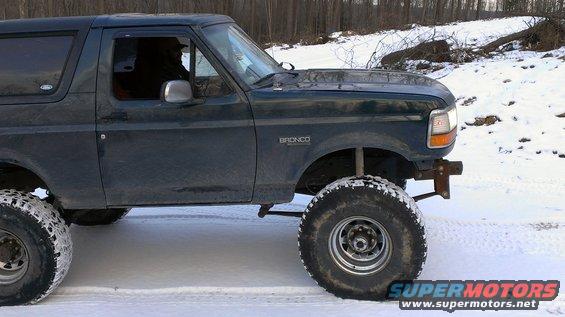 Dark green 1995 Ford Bronco with lifted suspension and large tires on a snowy road